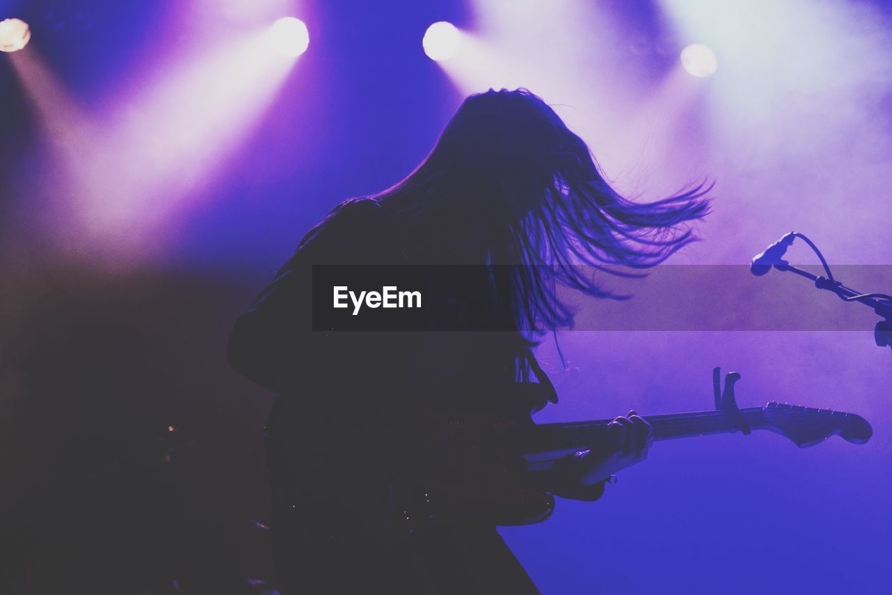 Musician playing guitar on stage