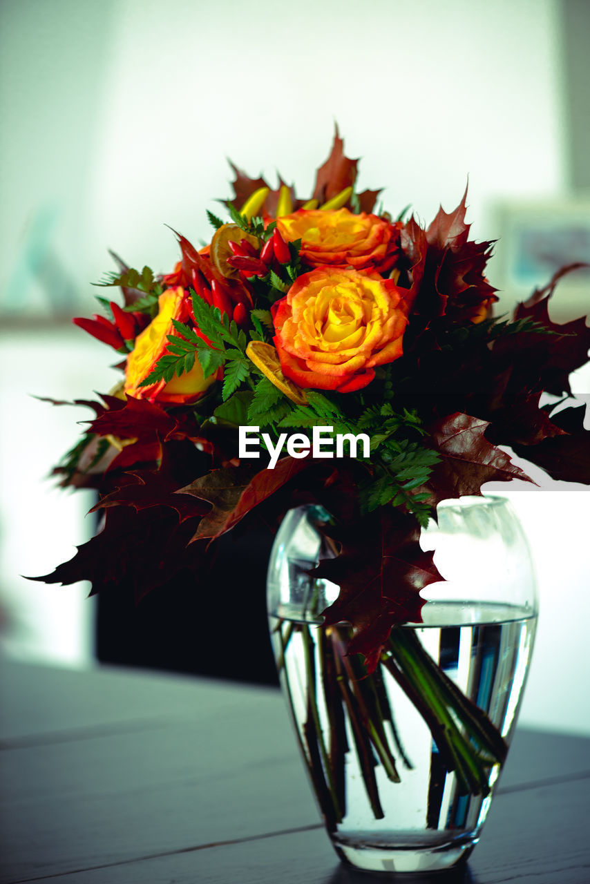 CLOSE-UP OF FLOWER VASE ON TABLE AGAINST WALL