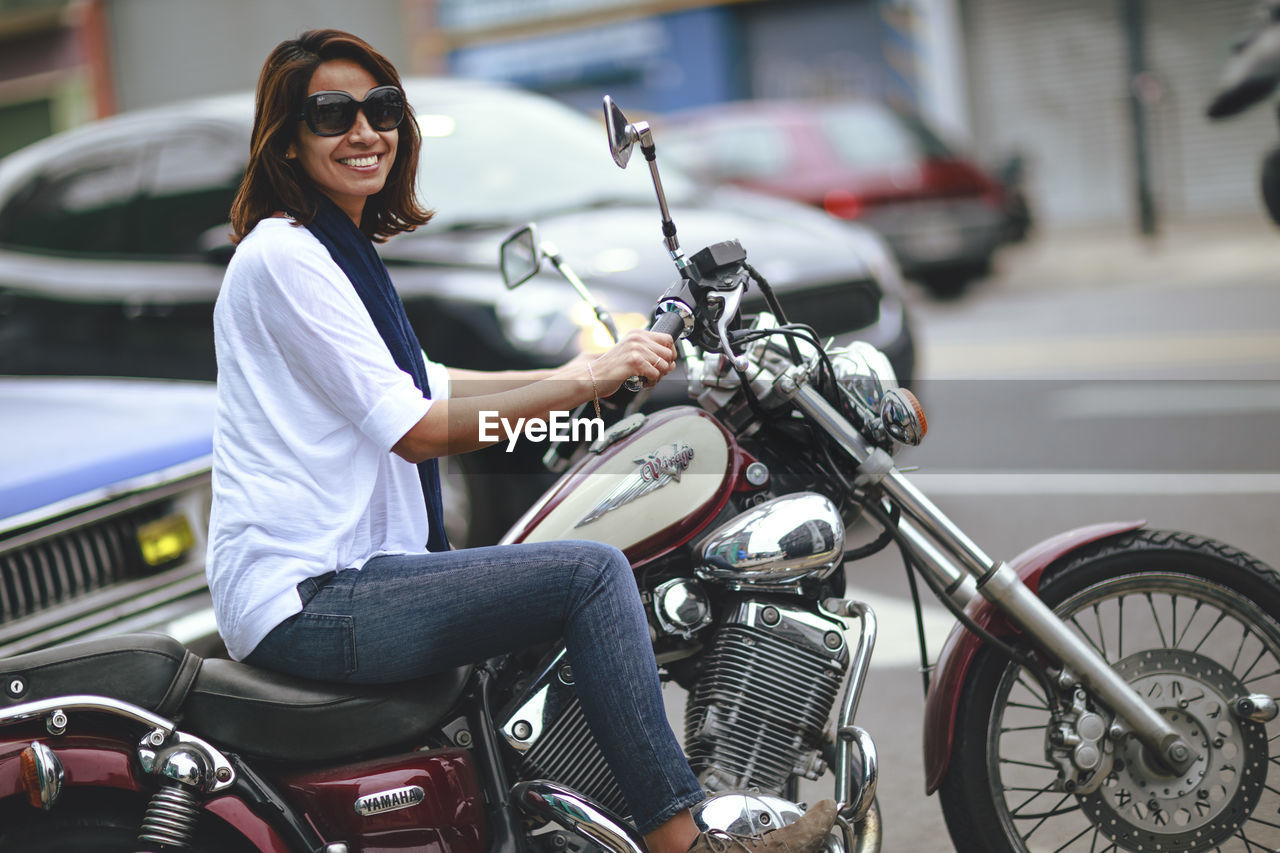 SIDE VIEW OF WOMAN SITTING ON MOTORCYCLE