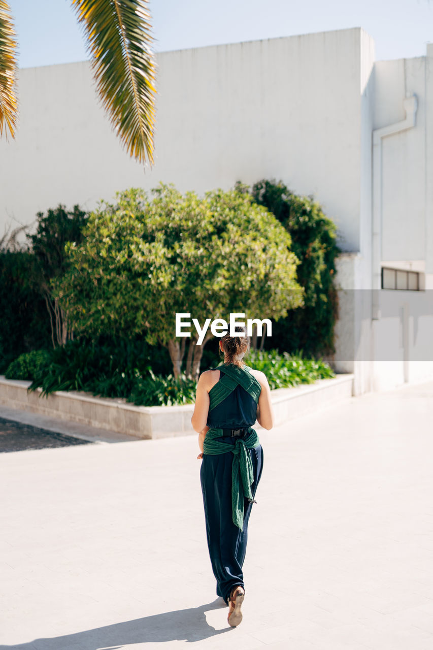 PORTRAIT OF WOMAN STANDING AGAINST PLANTS