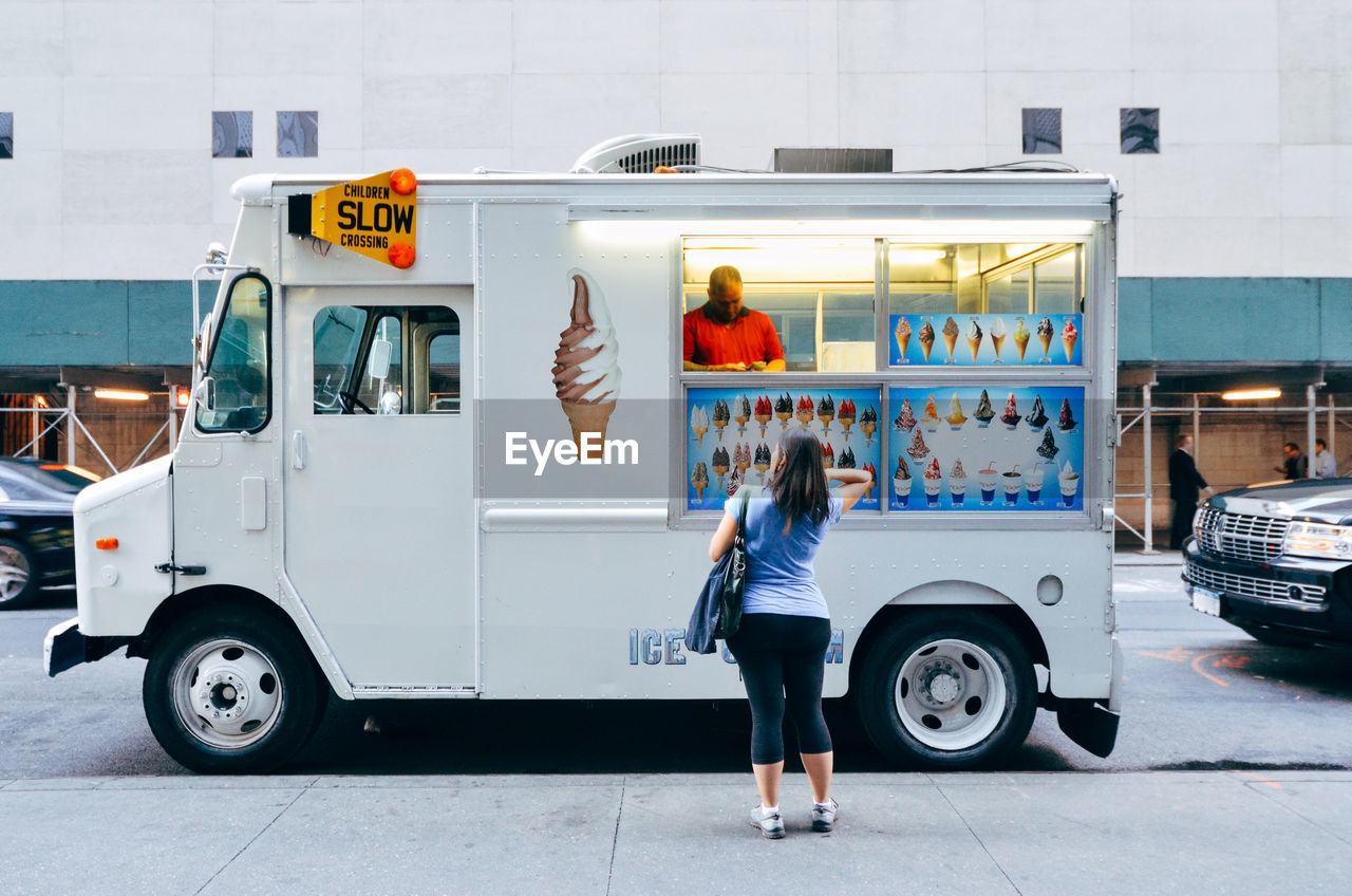 Rear view of woman buying from food truck salesman