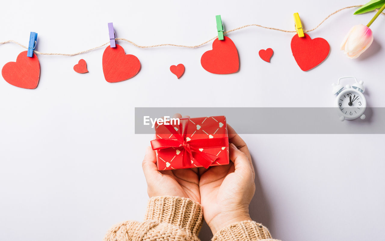 low section of woman holding heart shape against pink background