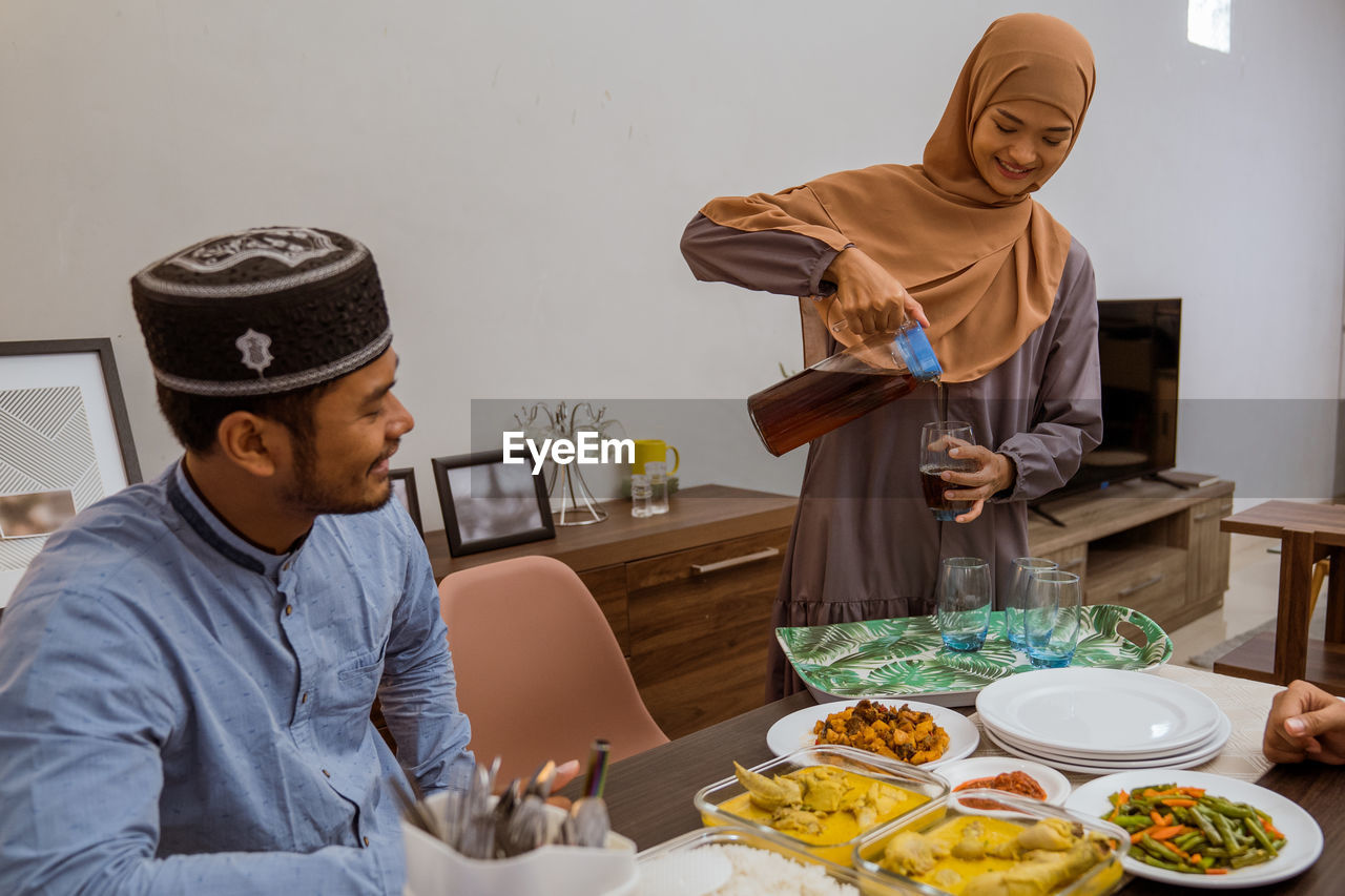 Woman pouring drink in glass during dinner