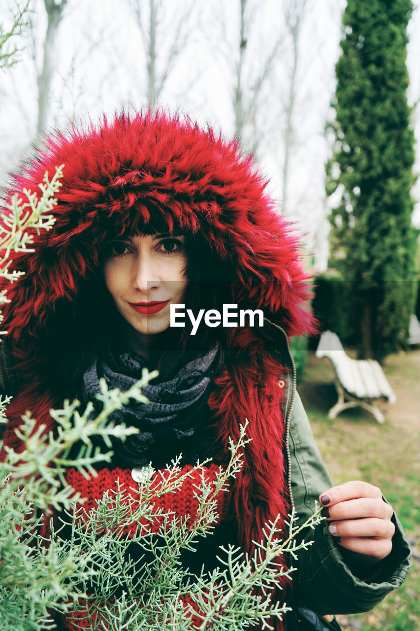 Portrait of woman in fur coat standing by plants in forest