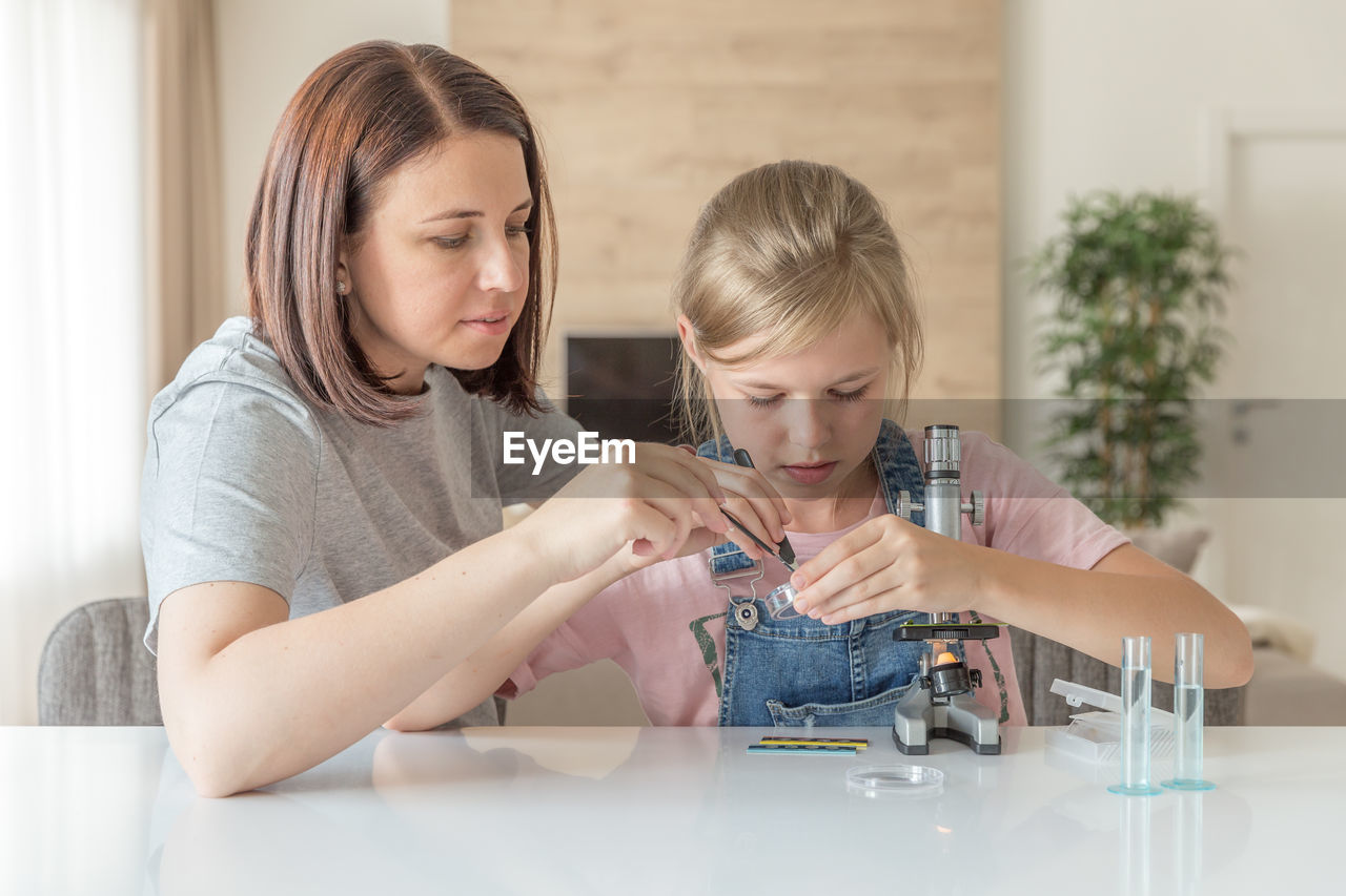 Mother helping daughter in science project at home