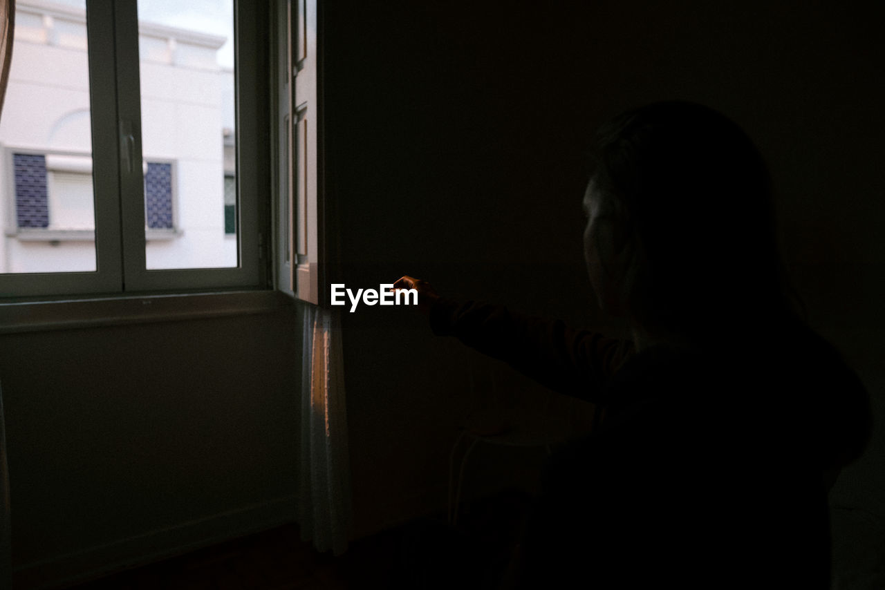SIDE VIEW OF MAN LOOKING AT WINDOW