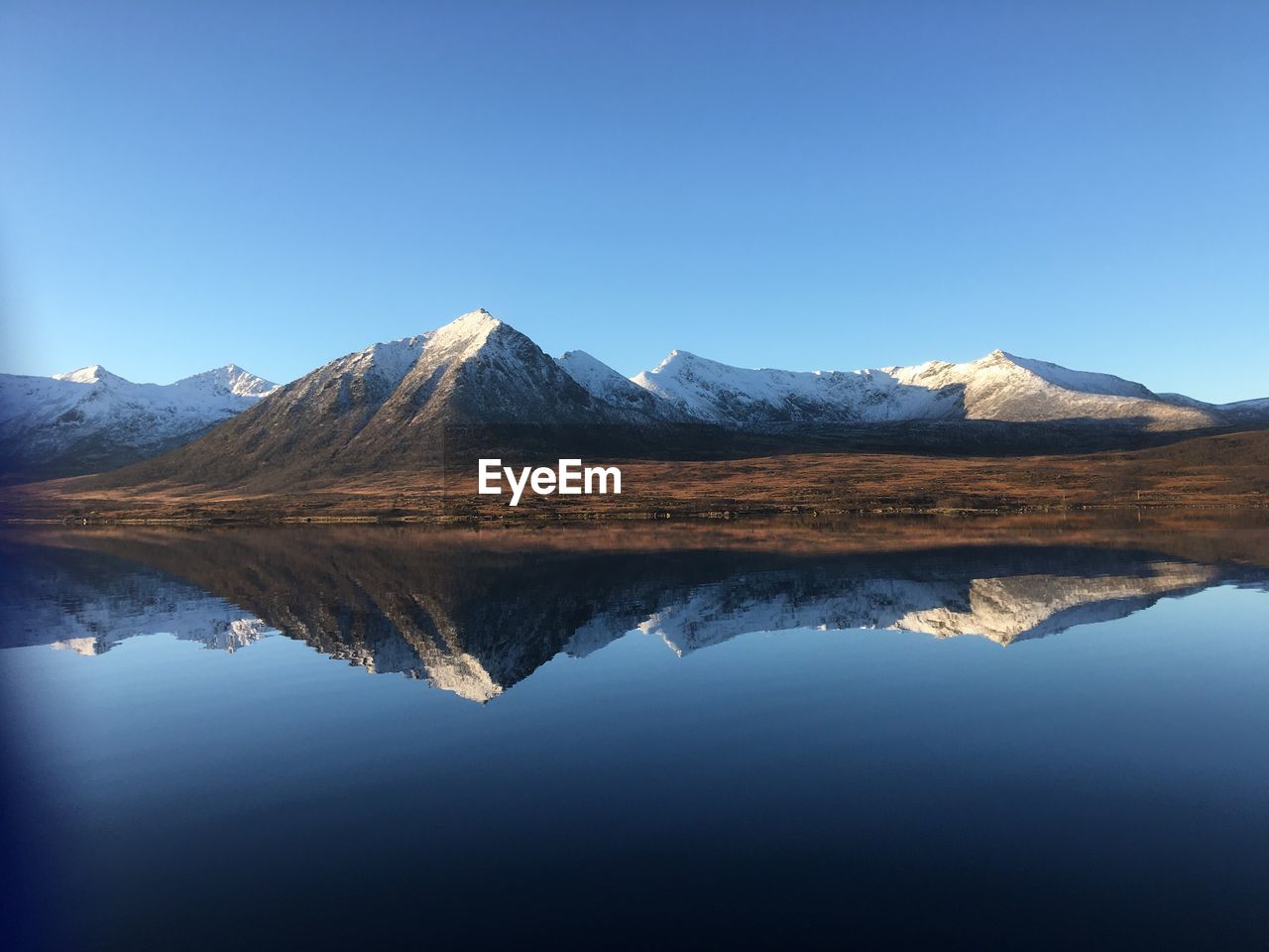 Reflection of mountains in lake against clear blue sky