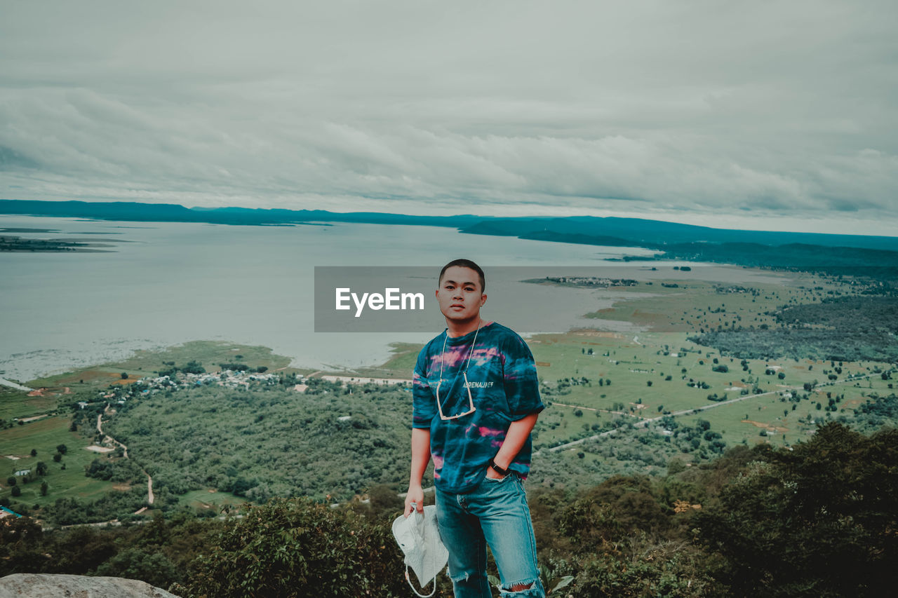 YOUNG MAN STANDING AGAINST SKY