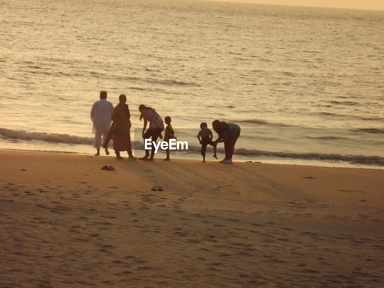 Family enjoying on sea shore during sunset