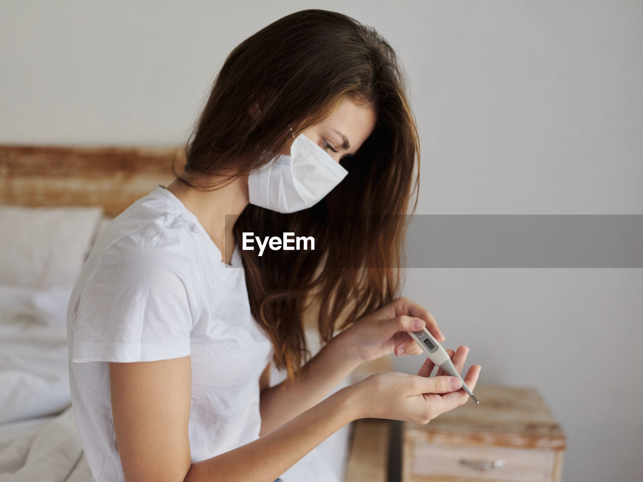 Young woman looking away while standing against white wall