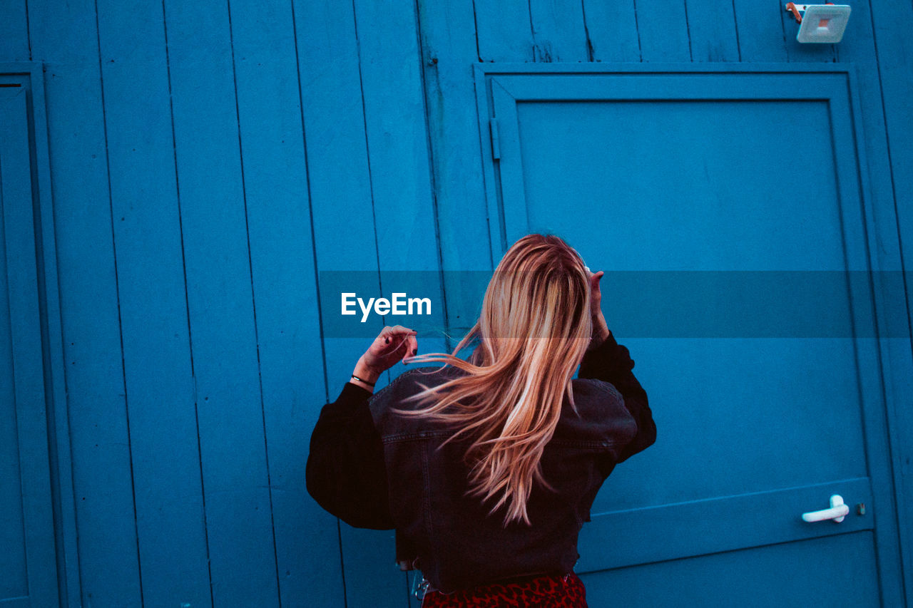 Rear view of woman standing against blue wall