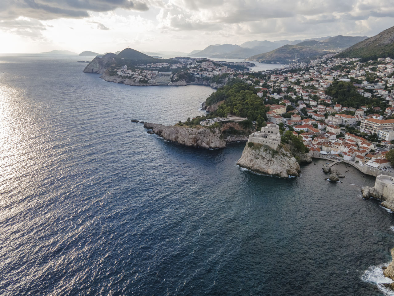 HIGH ANGLE VIEW OF TOWNSCAPE AND SEA AGAINST SKY