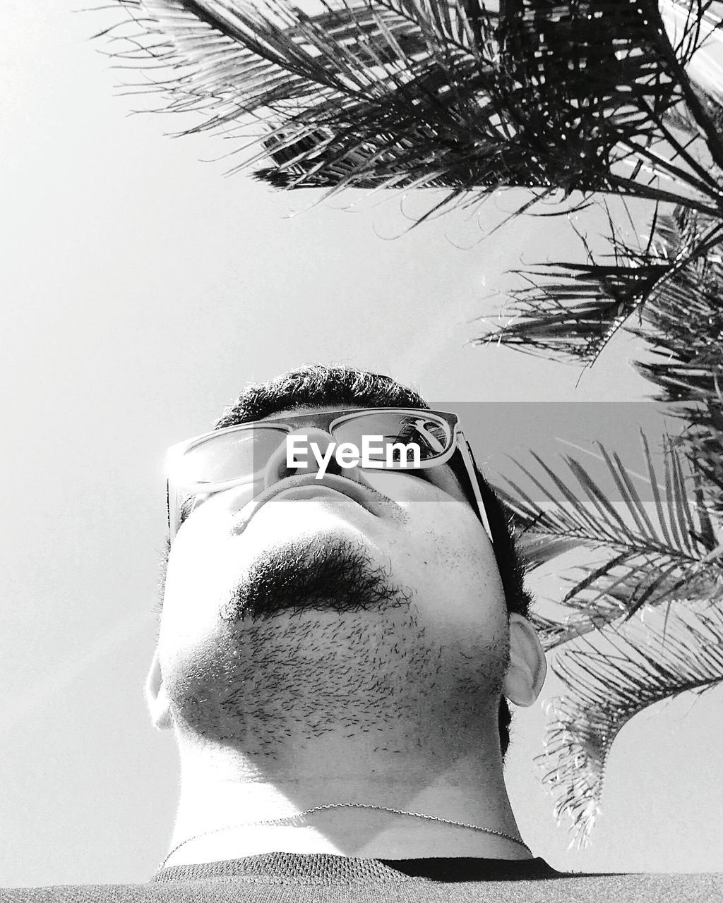 CLOSE-UP OF MAN WITH REFLECTION OF TREE AGAINST SKY