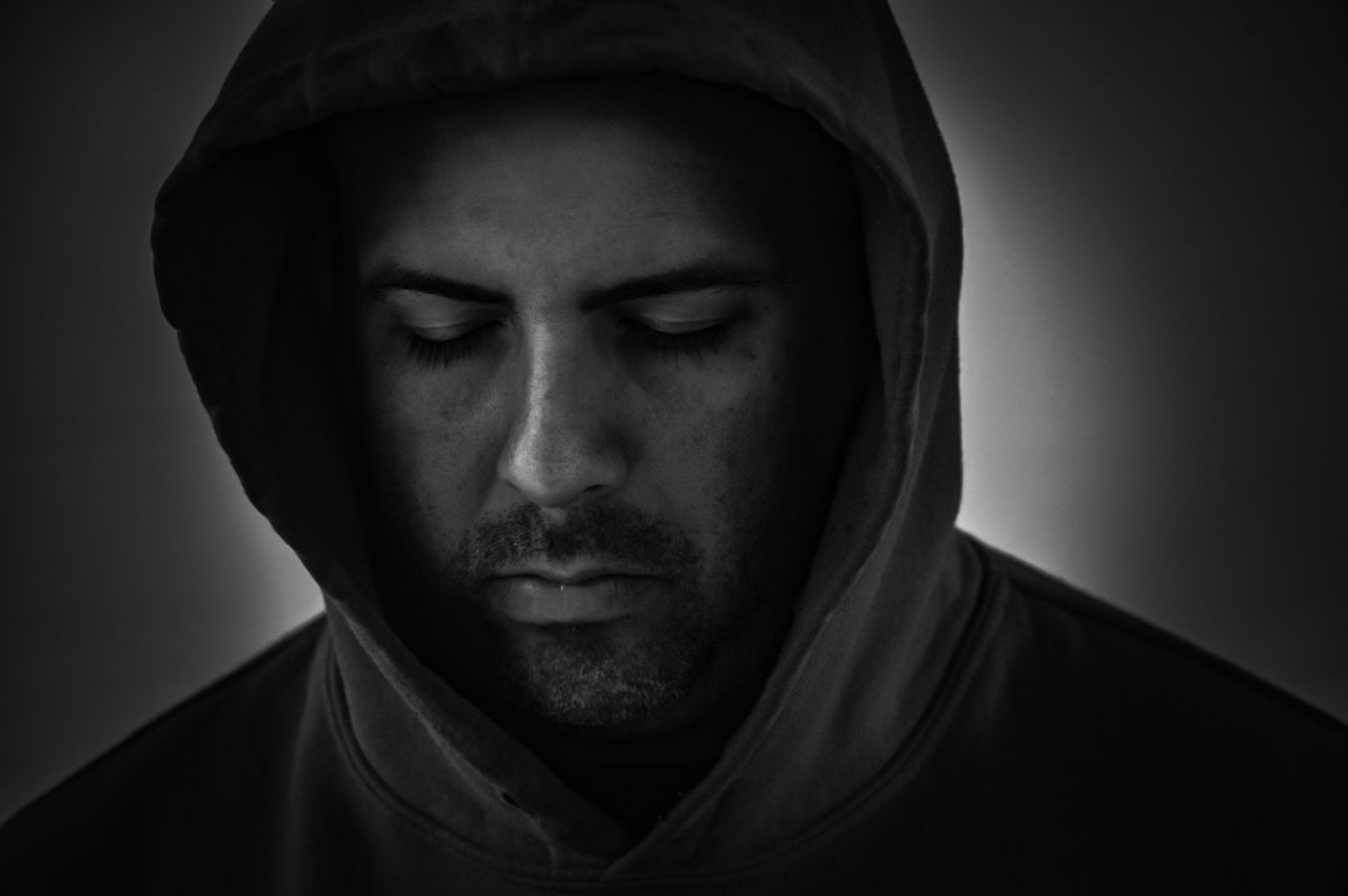 Serious man wearing hood against gray background