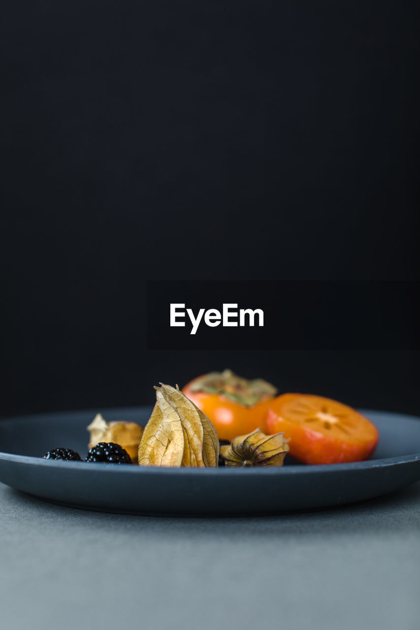 Physalis or cape gooseberries, blackberries and kumquats on a plate as a healthy snack