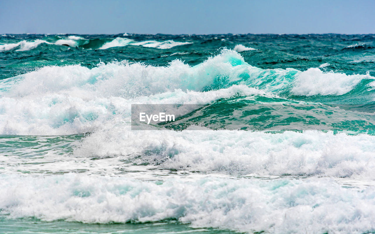 Turquoise colour ocean wave in windy day.