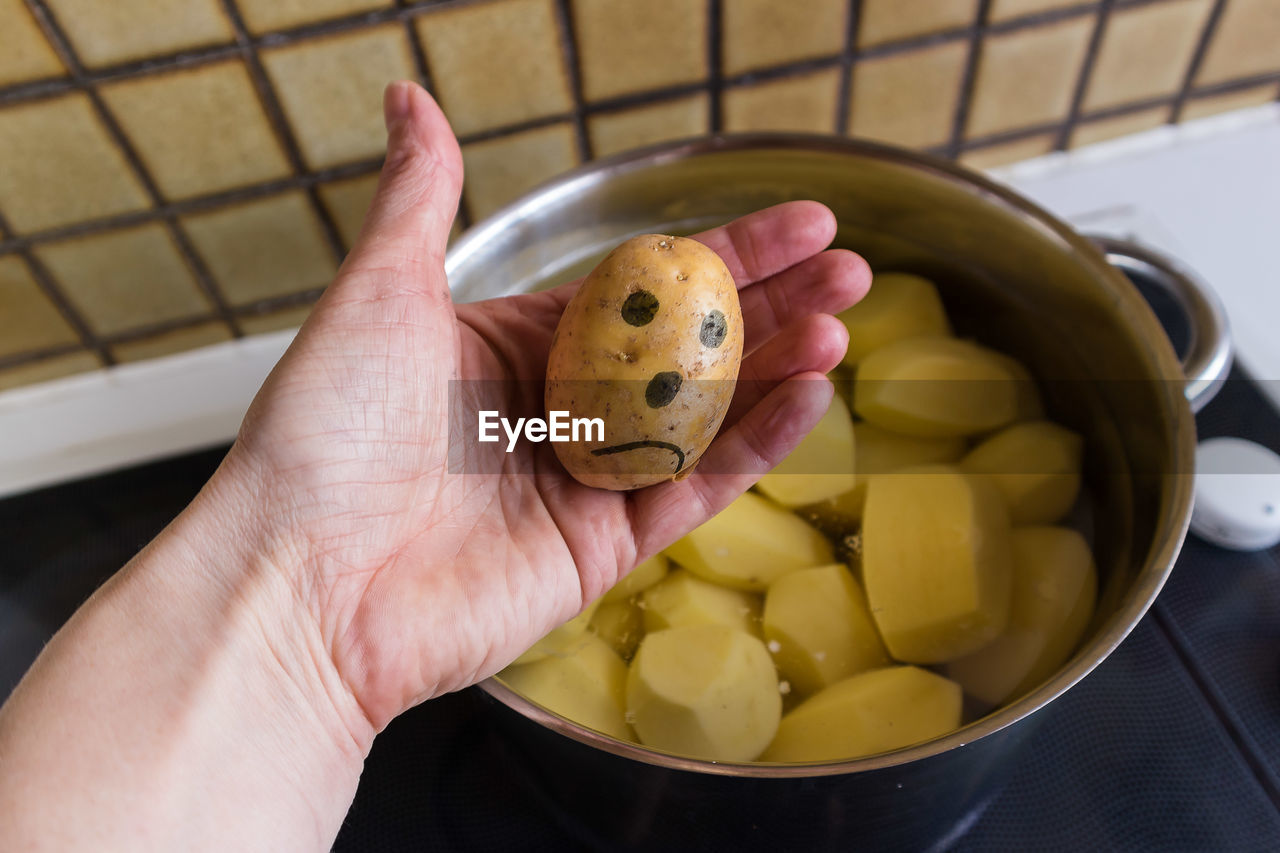 Close-up of hand holding potato over bowl