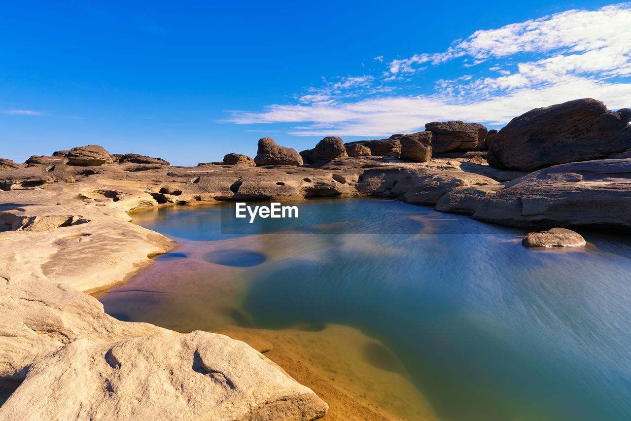 Rock formations in sea against blue sky