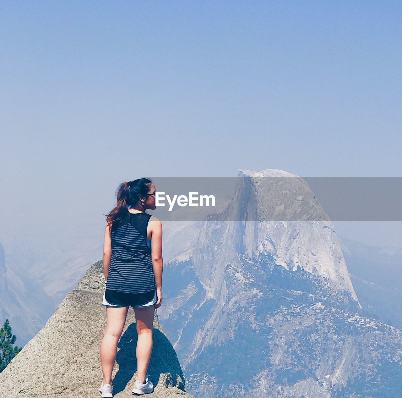 Rear view of woman standing on mountain peak with half dome in yosemite national park against sky