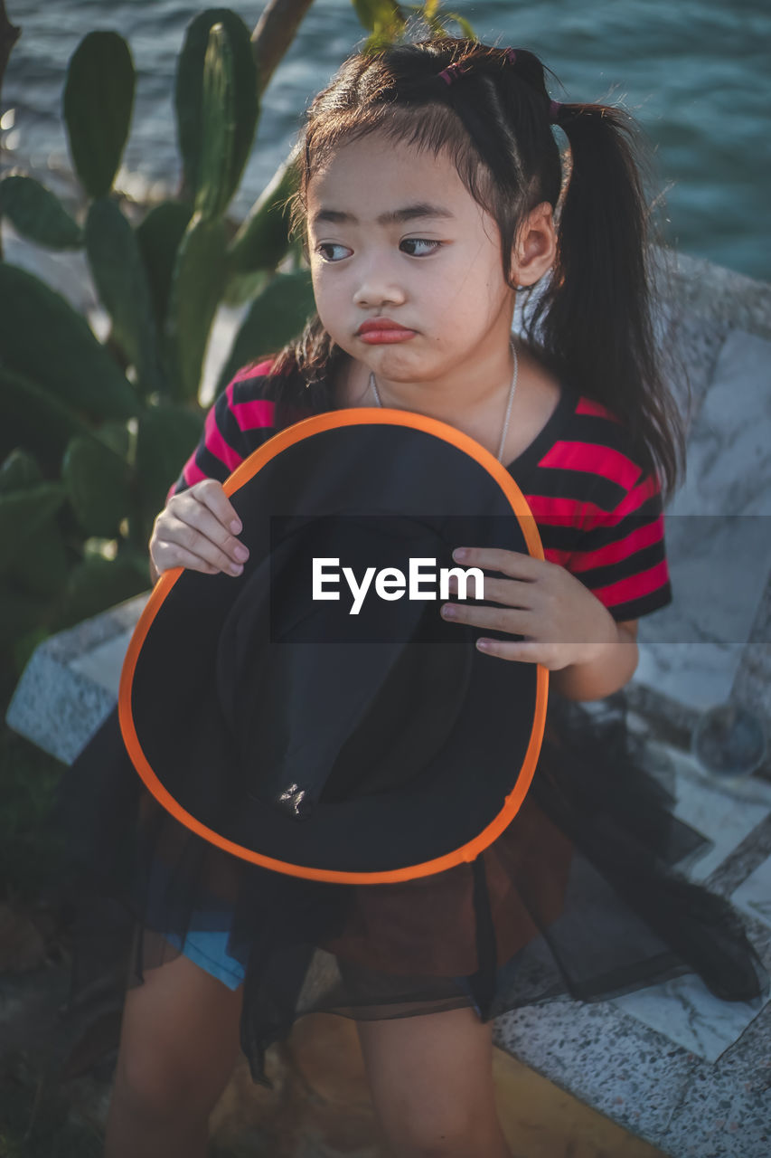 Girl holding witch hat looking away