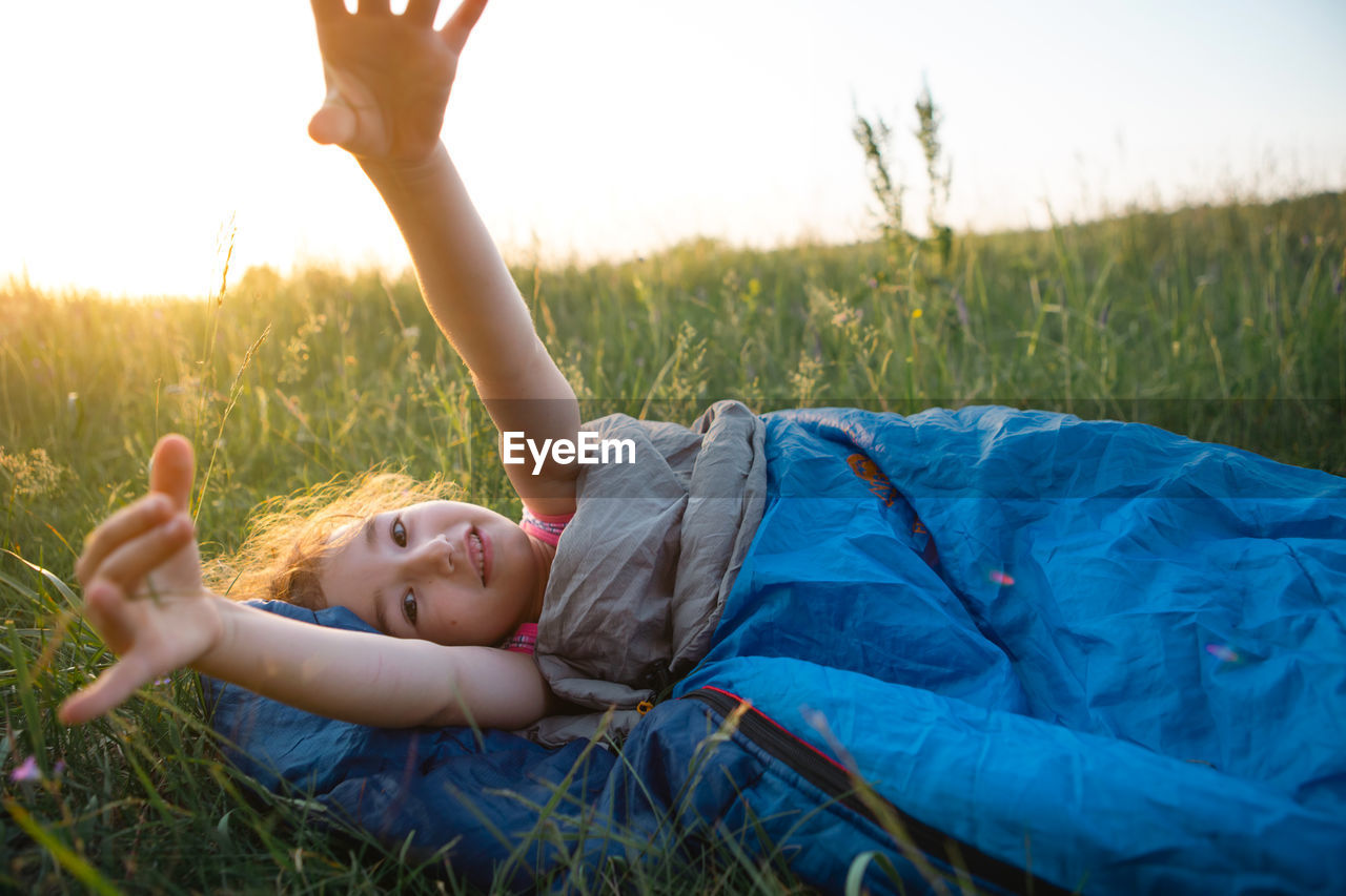 Cute girl in sleeping bag on field