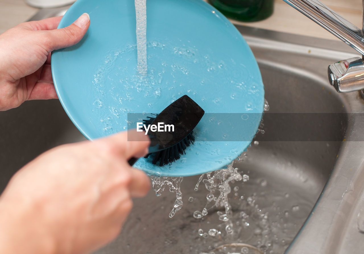 Cropped hands cleaning dish