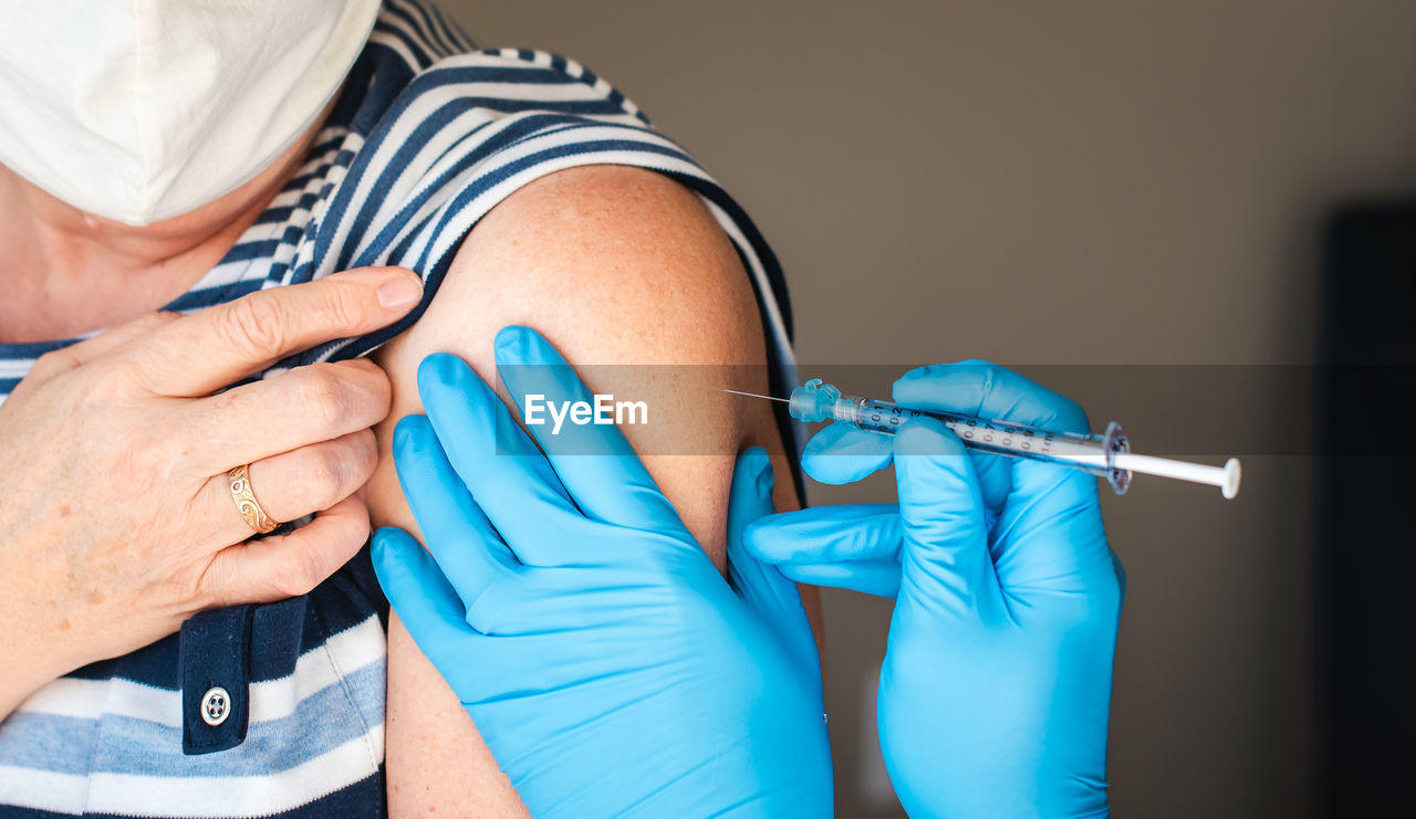 Close up of woman getting injected with a vaccine in upper arm.