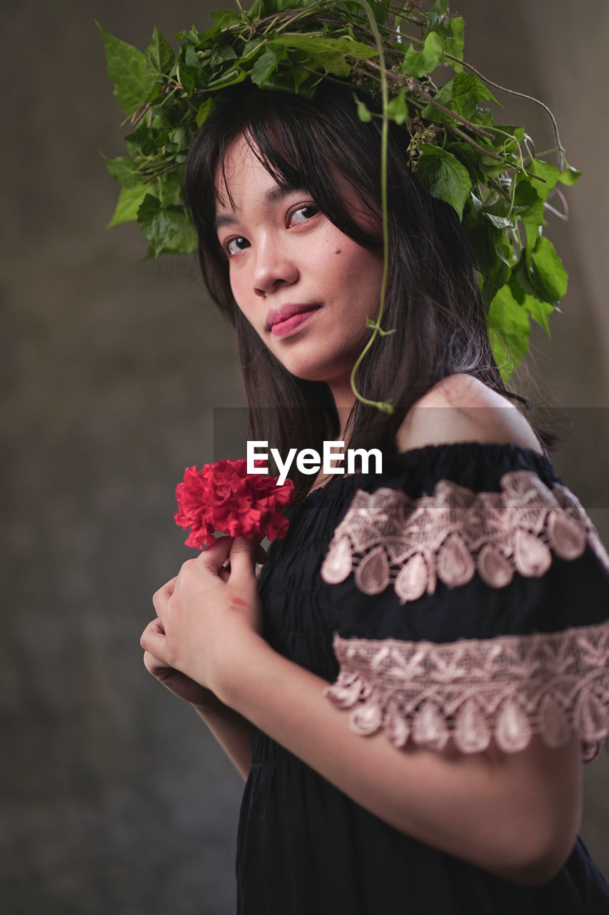 Portrait of woman holding red flower