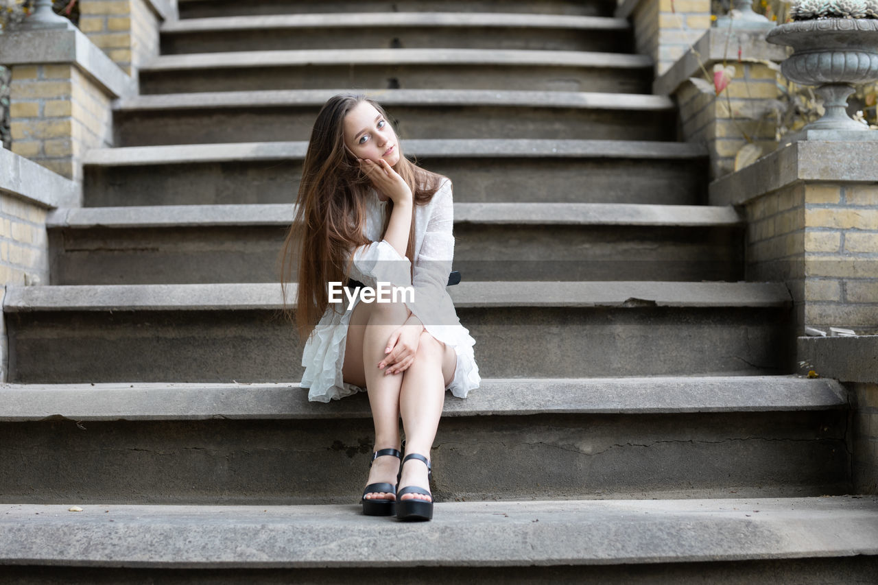 Full length of young woman sitting on staircase