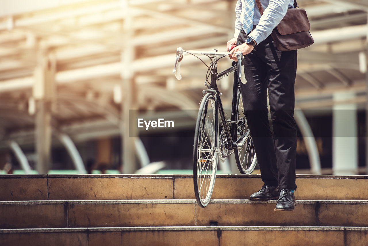 LOW SECTION OF MAN STANDING BY BICYCLE ON RAILING