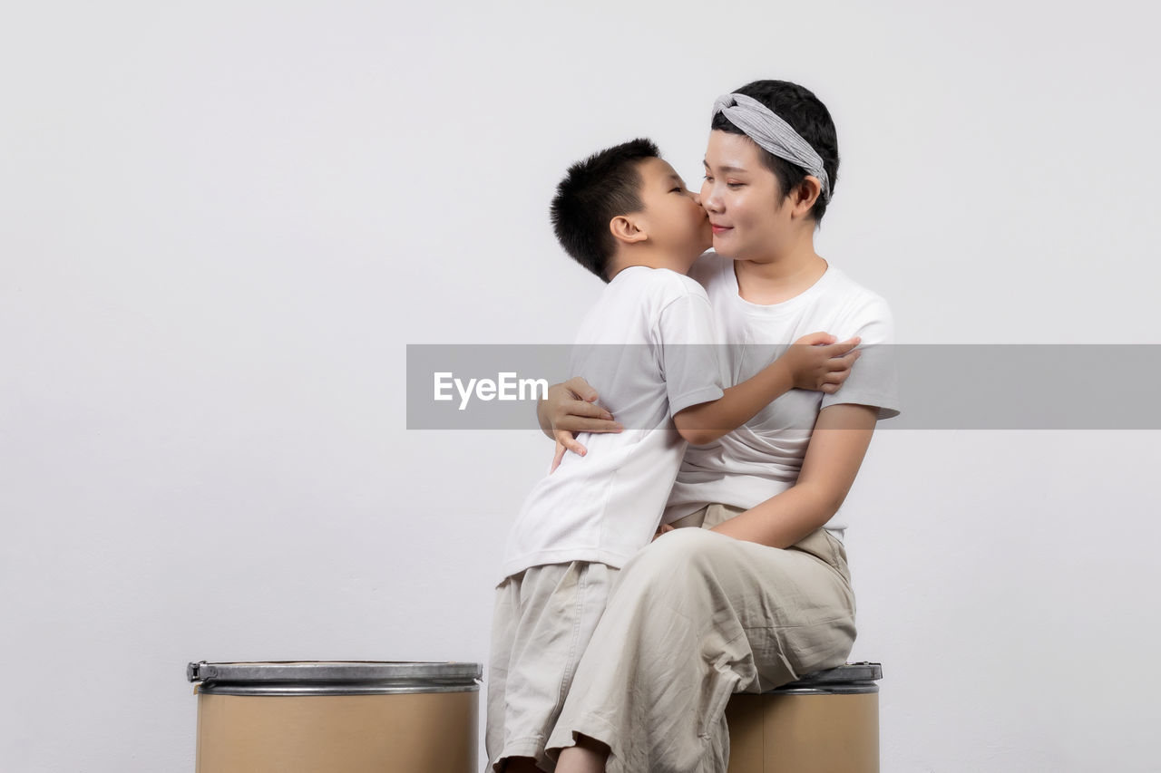 REAR VIEW OF COUPLE SITTING AGAINST GRAY BACKGROUND