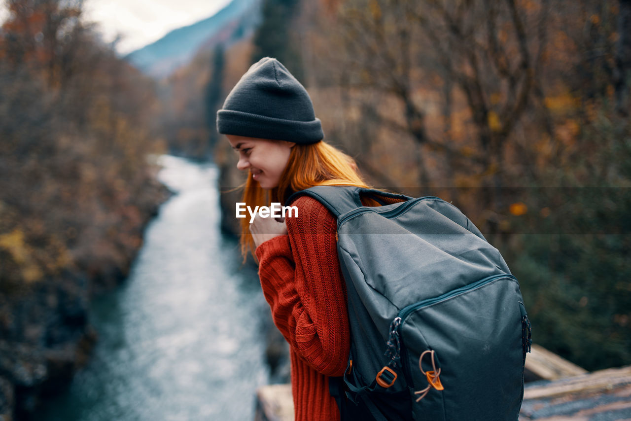 YOUNG WOMAN LOOKING AWAY WHILE STANDING IN PARK DURING WINTER