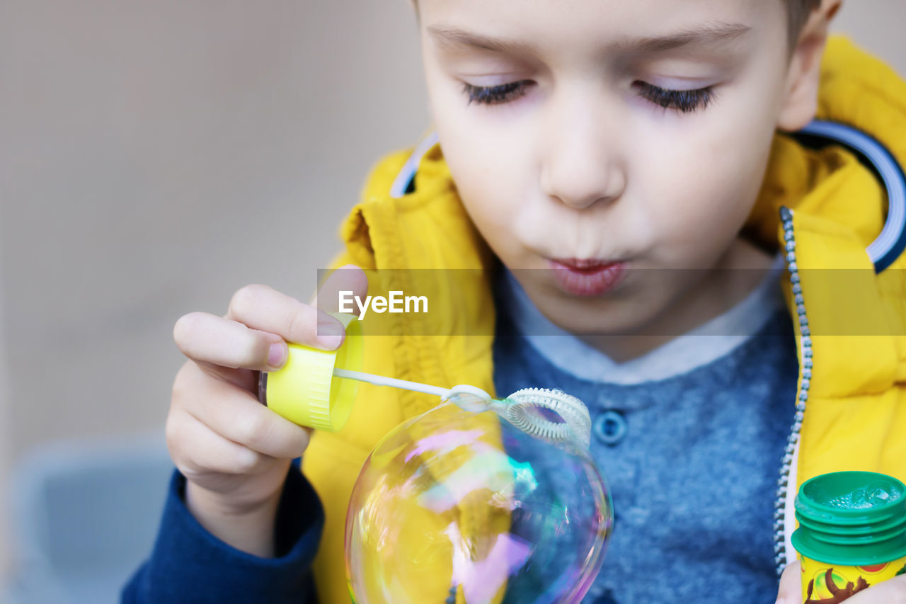 Close-up of kid blowing bubbles with bubble wand.