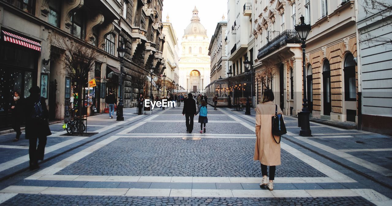 Rear view of people walking on street against st stephens basilica