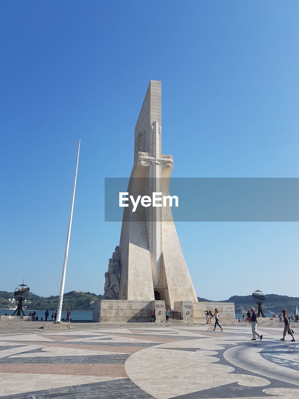 People at historical building against clear blue sky