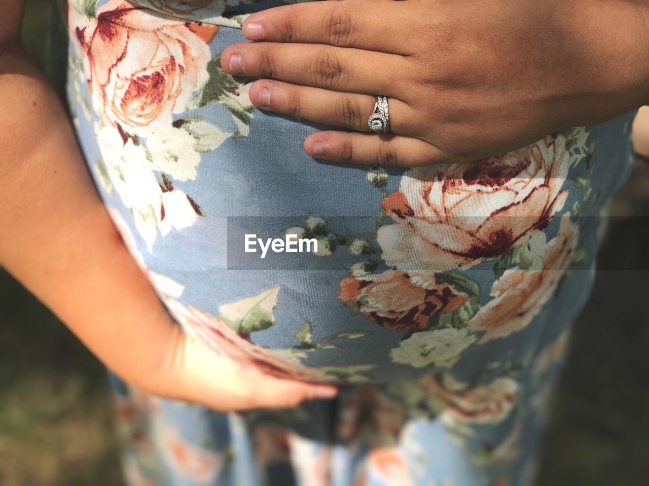 Close-up midsection of pregnant woman with hands on abdomen