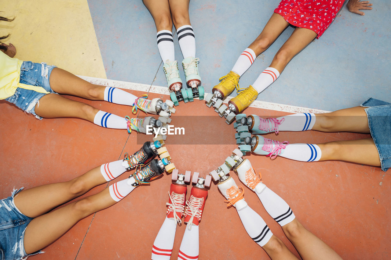 Legs of women wearing roller skates making circle at sports court