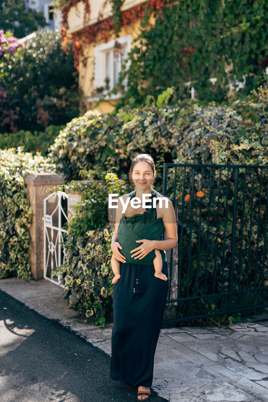 PORTRAIT OF BEAUTIFUL WOMAN STANDING AGAINST PLANTS