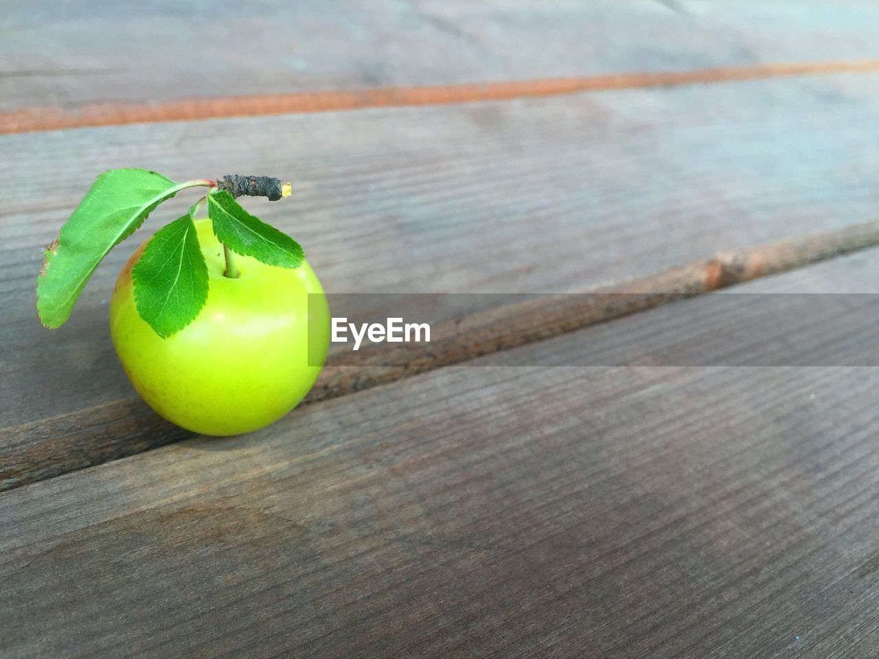 High angle view of green plum on hardwood floor