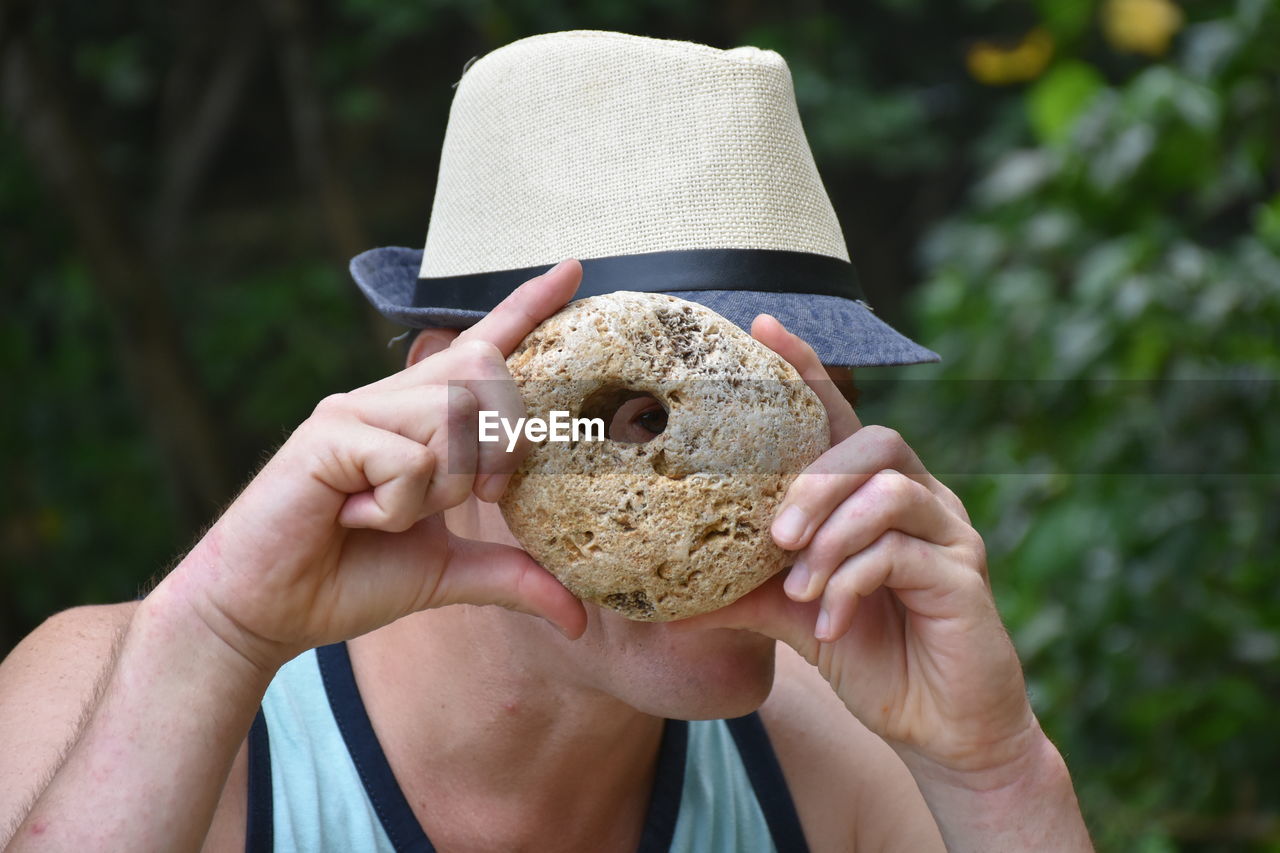 Close-up of man looking through hole in stone