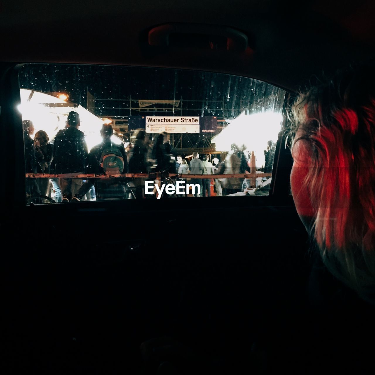 Woman in car watching people in city at night