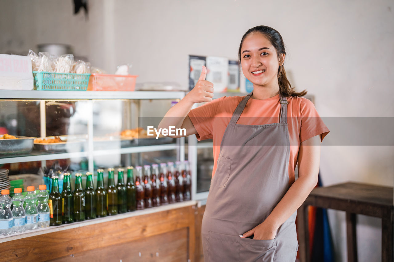 portrait of smiling young woman standing in bottles