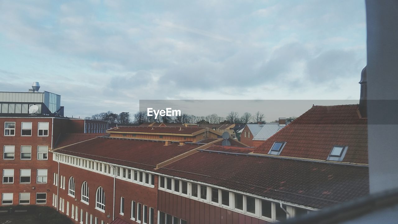 Houses against cloudy sky seen through glass window