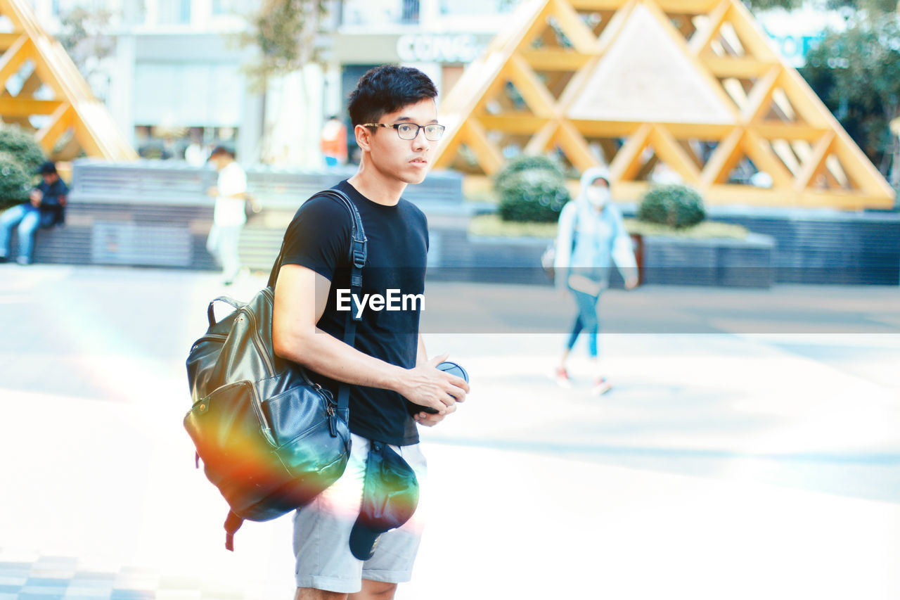 Young man with backpack on road in city