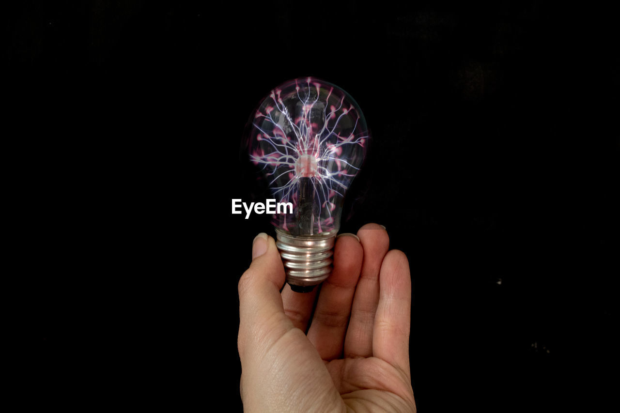 MIDSECTION OF PERSON HOLDING ILLUMINATED LIGHT BULB