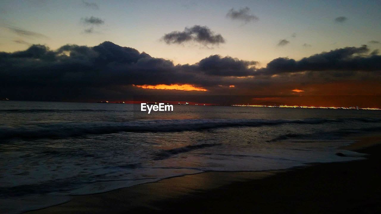 SCENIC VIEW OF BEACH AGAINST SKY AT SUNSET