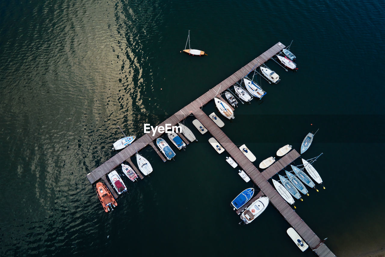 Aerial top view of boats near wooden pier at lake