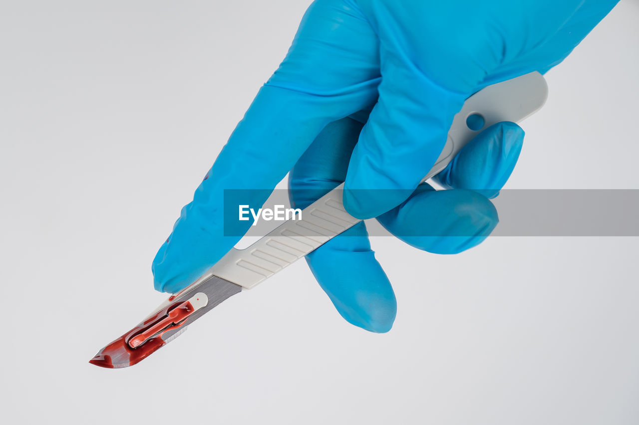 midsection of doctor holding equipment against white background