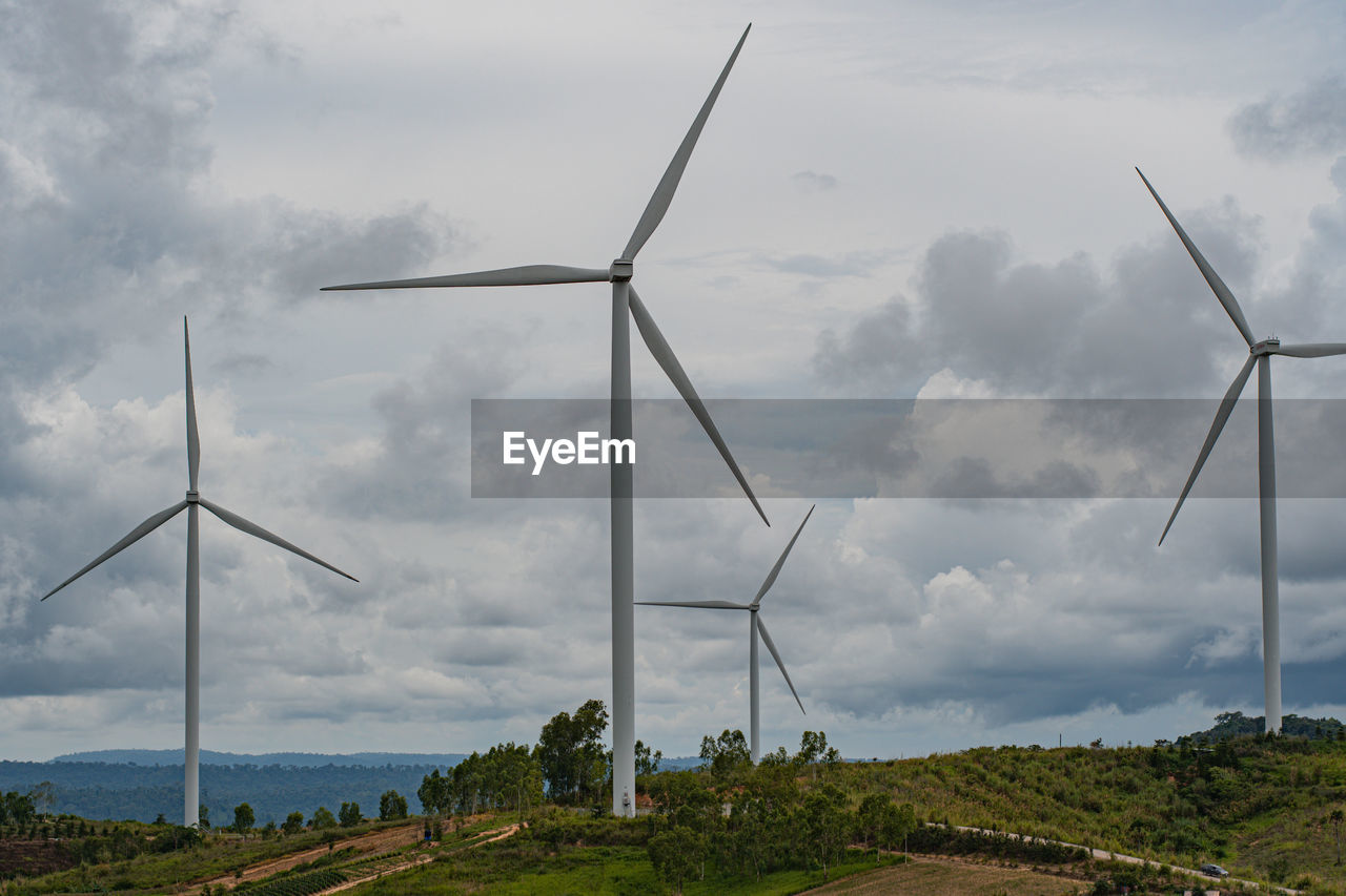 low angle view of windmills on field against sky