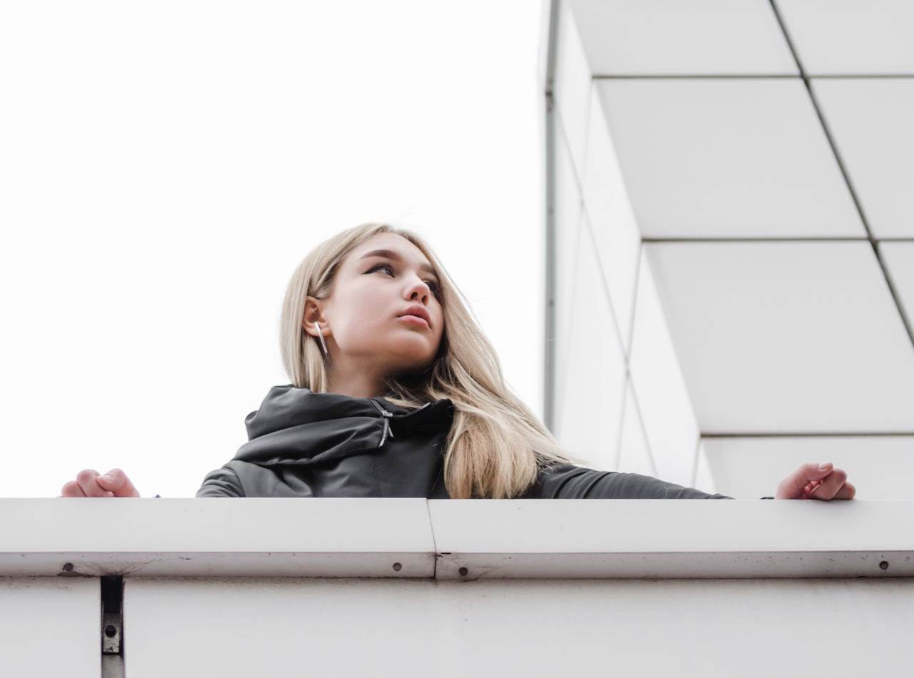 Low angle view of girl looking away by retaining wall